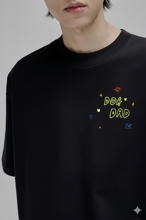 Black t-shirt with 'DOG DAD' text and colorful graphics worn by a person.